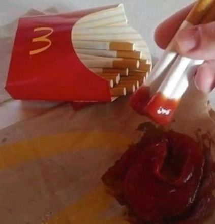 A mcdonalds chips box full of cigarettes. some are dipped in ketchup.